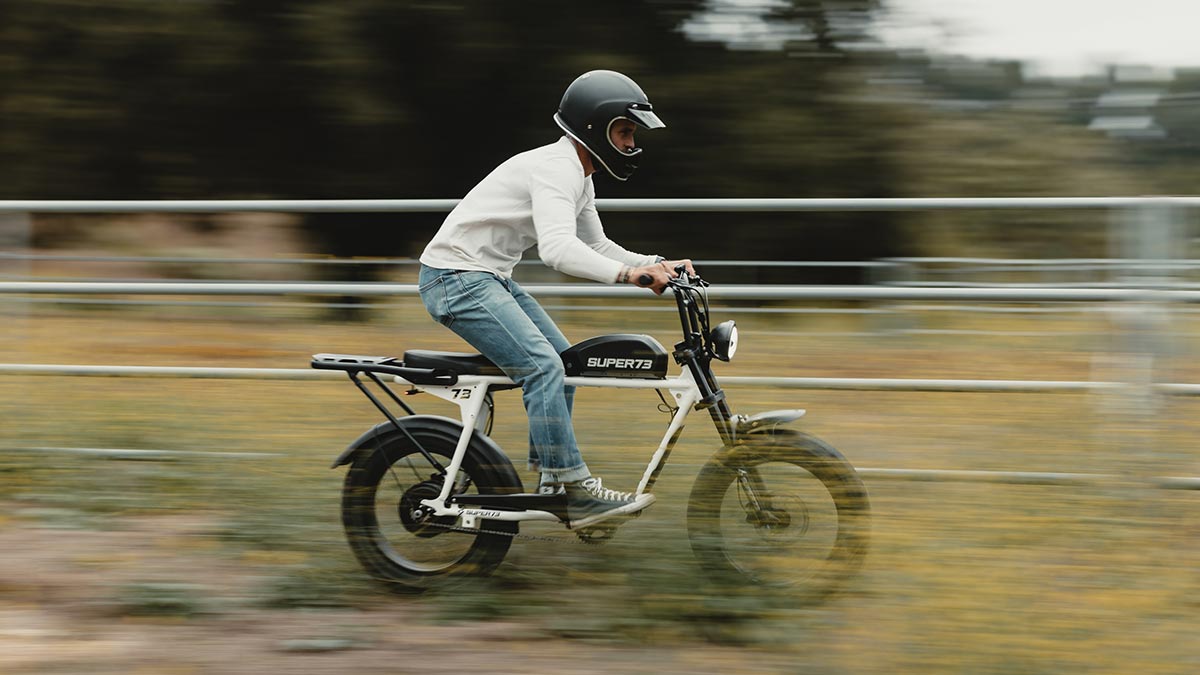 Young man riding a SUPER73-S series ebike standing on pedals showing suspension