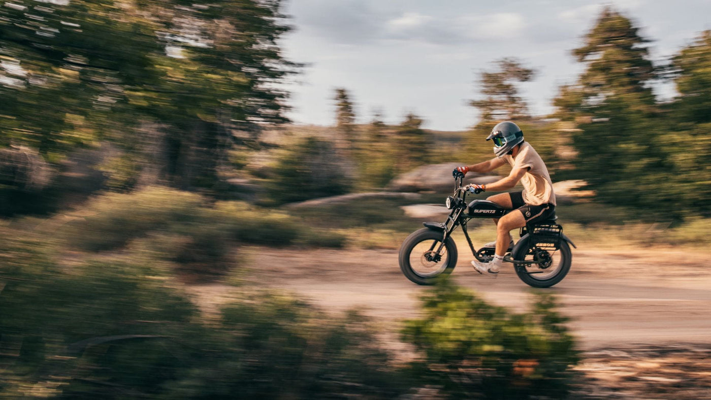 Man riding a Super73 S2 in the woods wearing a helmet