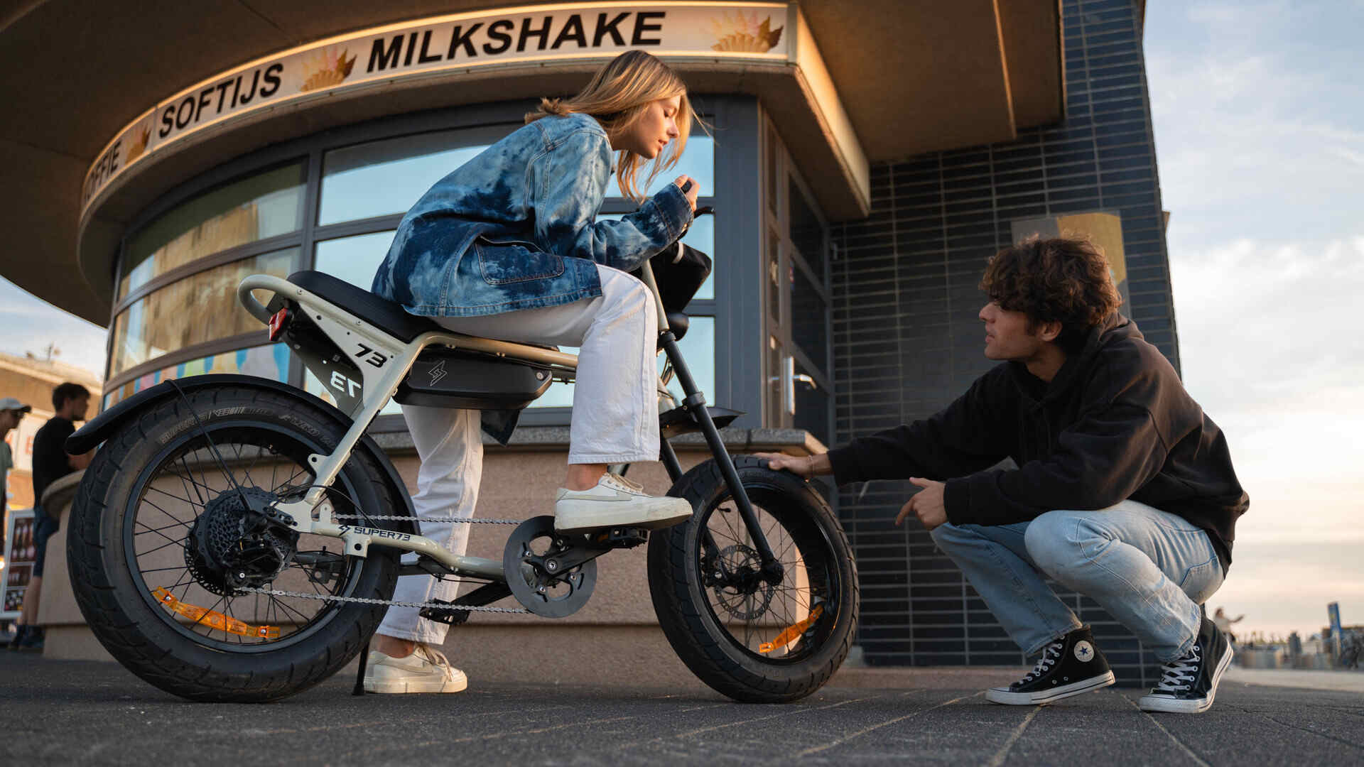 Girl on a Super73-ZX talking to a guy in front of a store