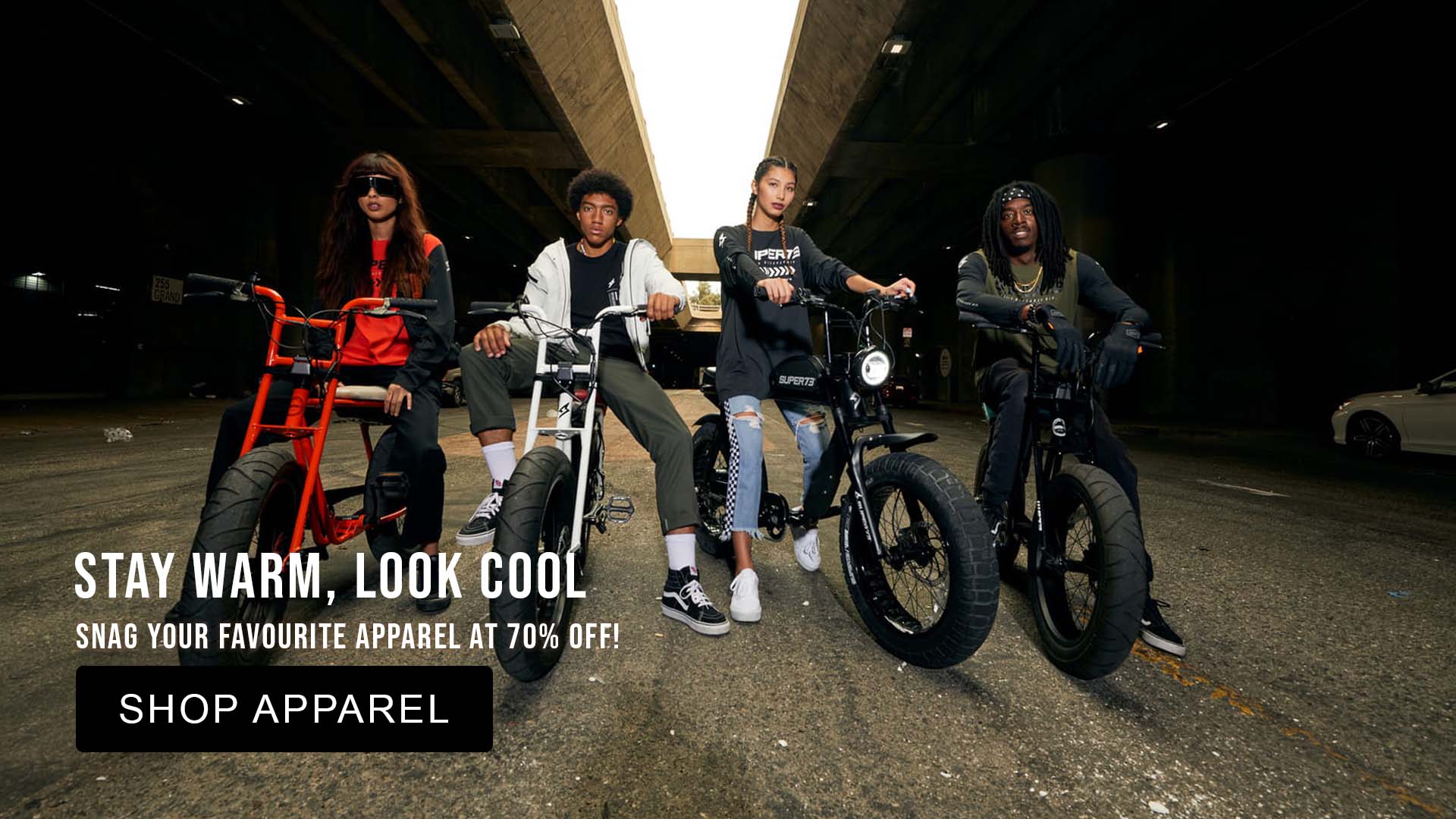 Four people on fat-tire bikes in a dark tunnel with super73 apparel discount promotional text overlay.