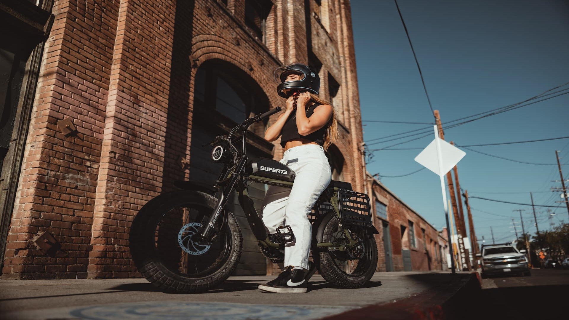 Woman is locking her helmet while seating on a Super73 ebike