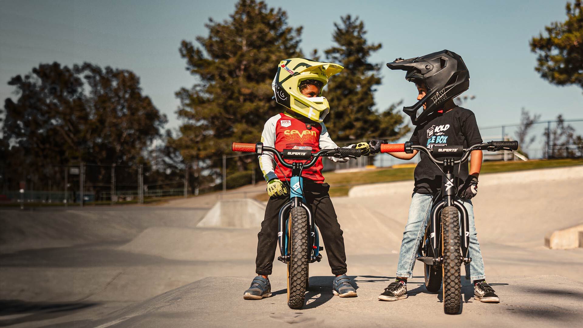 Two young riders with helmets on their SUPER73 K1D bikes.