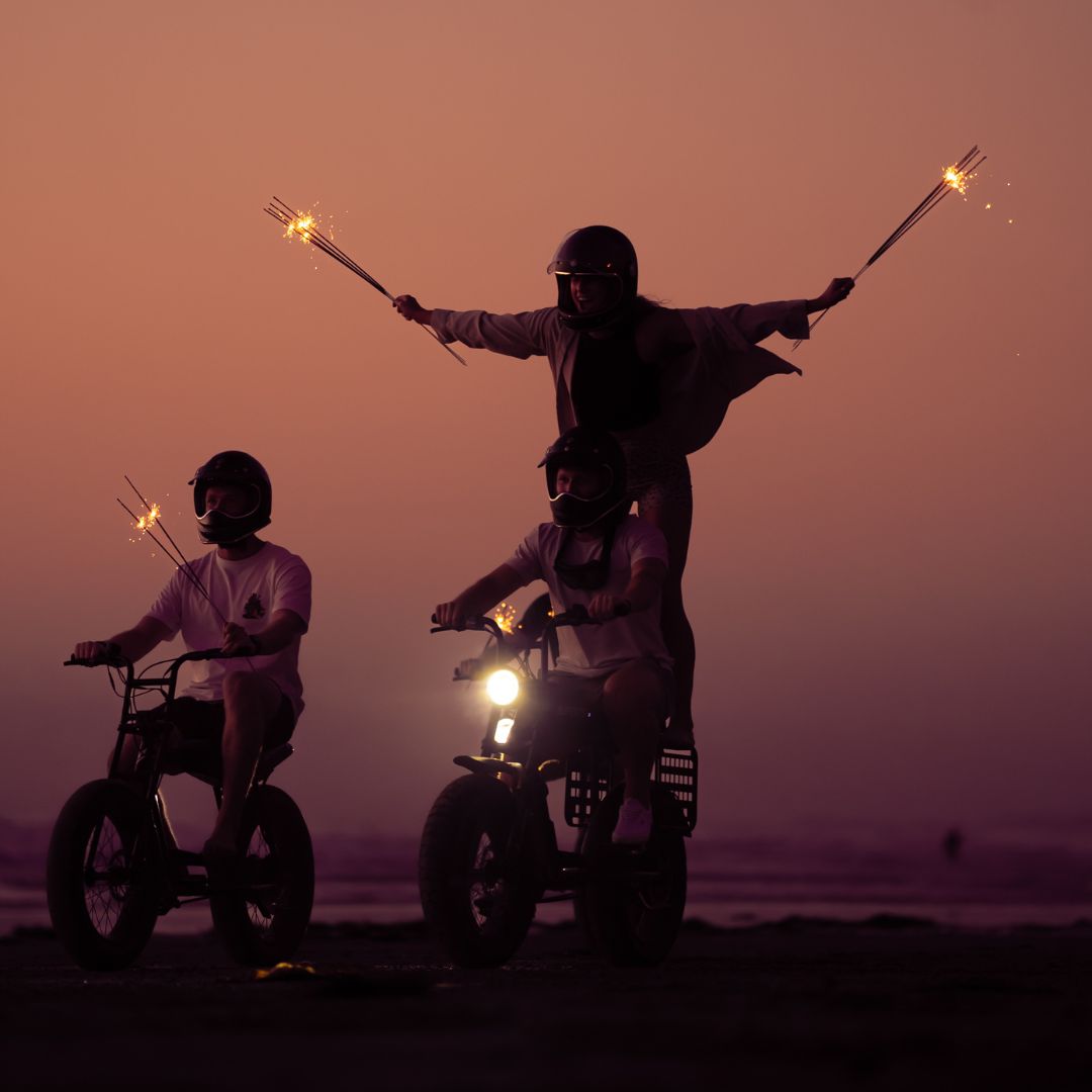 Group of people riding a Super73 in the sunset with fireworks