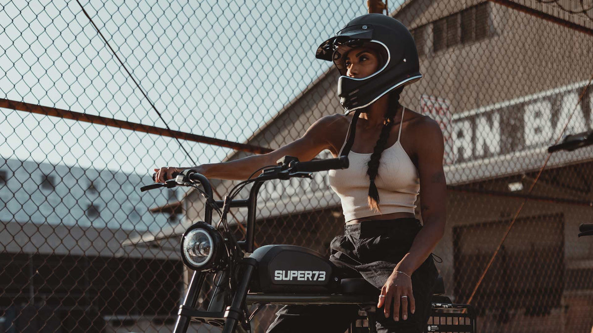 Rider posing on Super73 ebike in front of antique barn