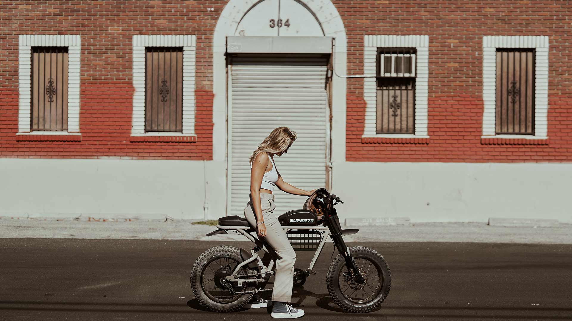 Rider posing with Super73 RX ebike in front of stylish brick building