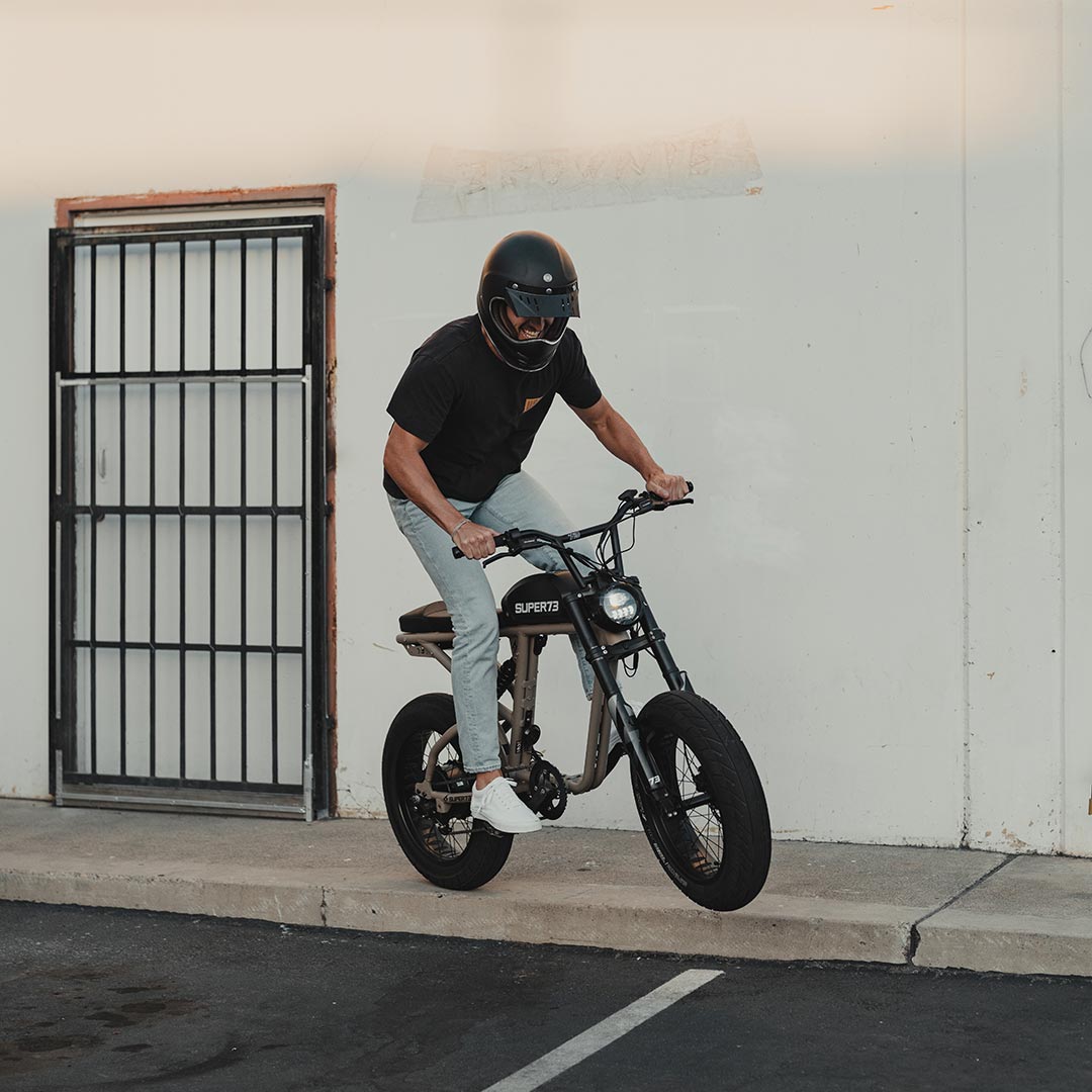 Helmeted rider going off 5 inch pure concrete curb on Super73 R Brooklyn ebike