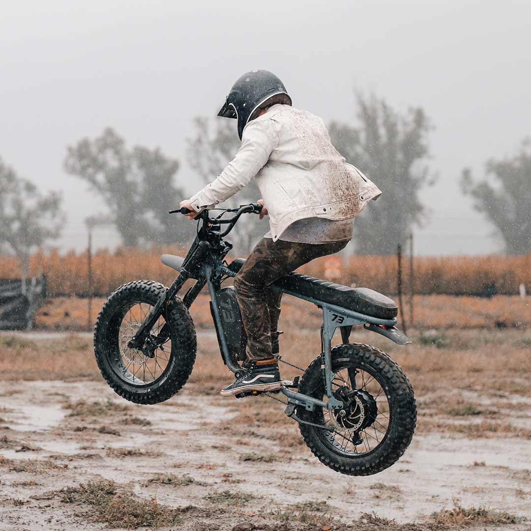Lifestyle image of a rider doing tricks on the S Adventure in the mud and wearing a helmet.